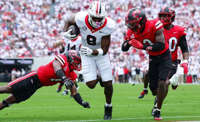Georgia tight end Ethan Barbour (9) scores a touchdown against Western Kentucky defensive backs Jaylen Lewis, left, and Christian White, right, during the first half of an NCAA college football game, Saturday, Sept. 12, 2026, in Athens, Ga. (AP Photo/Colin Hubbard)