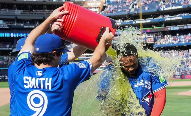 Toronto Blue Jays' Vladimir Guerrero Jr., right, is doused by Josh Smith (9) and Myles Straw, back left, after their team defeated the Baltimore Orioles in a baseball game in Toronto, Sunday, Sept. 13, 2026. (Nathan Denette/The Canadian Press via AP)