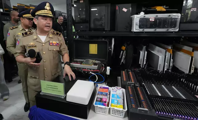 Major General Bun Sosekha, foreground, Deputy Phnom Penh Municipal Police chief, shows the evidence inside a room at the Phnom Penh Municipal Police headquarters, following an operation against scam centers in Phnom Penh, Cambodia, Tuesday, Sept. 22, 2026. (AP Photo/Heng Sinith)