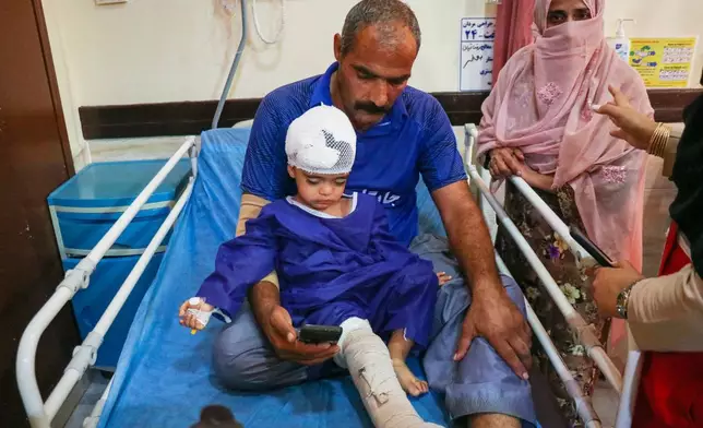 A man sits with a child injured, according to Iranian media, in a strike on a home where a wedding was being held in Kuhestak, southern Iran, at a hospital in Menab, Iran, early Wednesday, Sept.2, 2026. (Razieh Poudat/ISNA via AP)