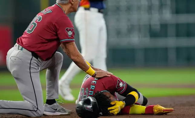 Arizona Diamondbacks' Geraldo Perdomo (2) holds his head as first base coach Dave McKay kneels beside him after being hit by a line drive by Ketel Marte during the third inning of a baseball game against the Houston Astros Sunday, Sept. 6, 2026, in Houston. (AP Photo/David J. Phillip)
