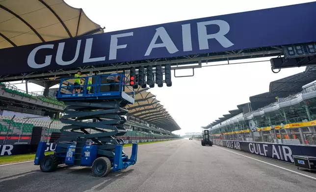 Workers use a scissor lift to install a banner over the track ahead of the Bahrain Grand Prix in Malaysia at the Sepang International Circuit in Sepang, Malaysia, Wednesday, Sept. 30, 2026. (AP Photo/Vincent Thian)