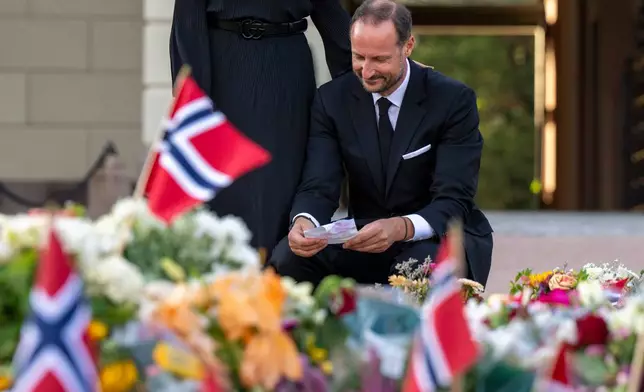 Norway's King Haakon reads greetings, that mourners have laid down in front of the Palace four days after the death of King Harald V., in Oslo Monday, Aug. 31, 2026. (Javad Parsa/NTB Scanpix via AP)