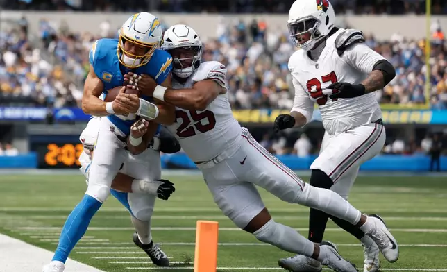 Los Angeles Chargers quarterback Justin Herbert, left, is hit by Arizona Cardinals linebacker Jack Gibbens, left rear, and linebacker Zaven Collins (25) as defensive tackle Walter Nolen III (97) follows the play during the first half of an NFL football game, Sunday, Sept. 13, 2026, in Inglewood, Calif. (AP Photo/Caroline Brehman)
