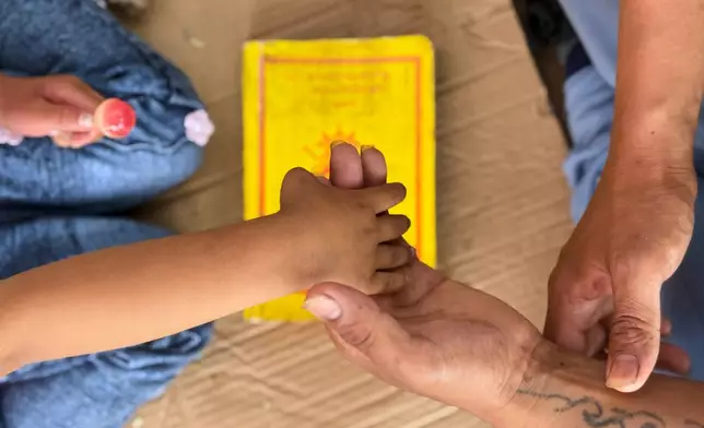Survivor Tsering Gelbu Lama holds his daughter's hand as they spend time at a monastery where hundreds of survivors are seeking refuge in Kathmandu, Nepal, Monday, Aug. 31, 2026. (AP Photo/Niranjan Shrestha)