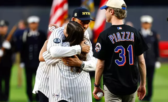 Derek Jeter hugs Brielle Saracini before she throws out the ceremonial first pitch with husband Sean McGuire before a baseball game between the New York Yankees and the New York Mets, Friday, Sept. 11, 2026, in New York. (AP Photo/Noah K. Murray)