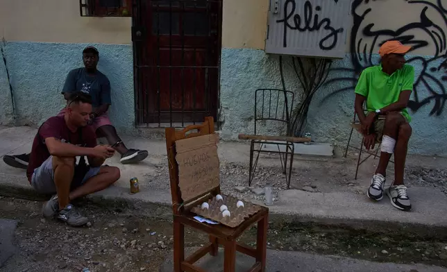 People hang out near eggs for sale on a street during a blackout in Havana, Cuba, Friday, Sept. 18, 2026. (AP Photo/Ramon Espinosa)