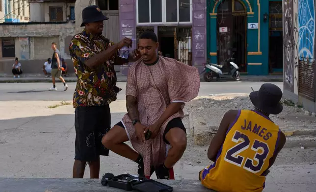 A barber provides service to a client on a street during a blackout in Havana, Cuba, Friday, Sept. 18, 2026. (AP Photo/Ramon Espinosa)