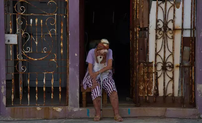 An elderly woman sits in the doorway of her home to catch the cool air during a blackout in Havana, Cuba, Friday, Sept. 18, 2026. (AP Photo/Ramon Espinosa)