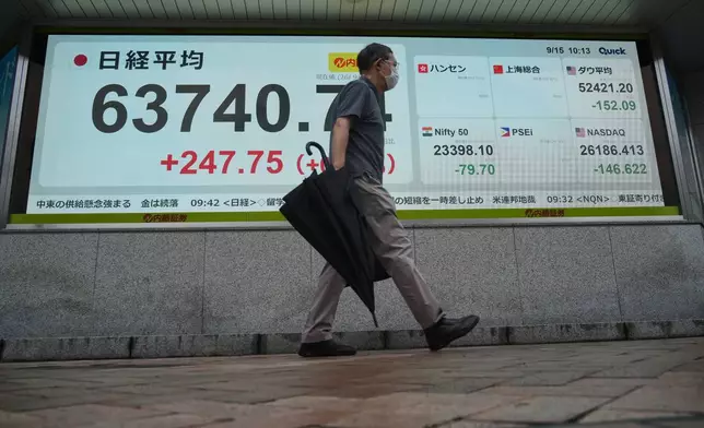 A person walks in front of an electronic stock board showing Japan's Nikkei index at a securities firm Tuesday, Sept. 15, 2026, in Tokyo. (AP Photo/Eugene Hoshiko)