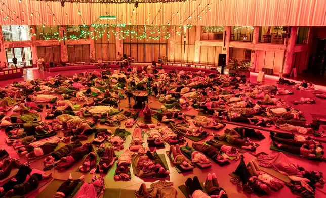 People lay on mattresses as Belgian composer Mattias Devriendt performs at Wintercircus in Ghent, Sunday, Sept. 20, 2026. (AP Photo/Harry Nakos)