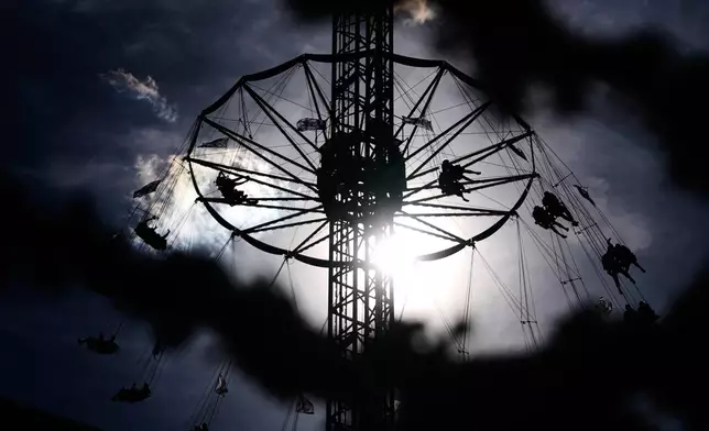 People ride a swing carousel at opening day of the 191st Oktoberfest beer festival in Munich, Germany, Saturday, Sept. 19, 2026. (AP Photo/Matthias Schrader)