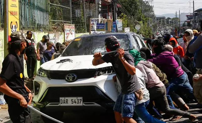 A group attacks a vehicle from an opposing group outside a school used as a polling center during the Bangsamoro Autonomous Region in Muslim Mindanao parliamentary elections in Cotabato city, southern Philippines, Monday, Sept. 14, 2026. (AP Photo)