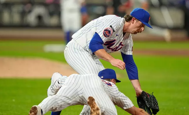 New York Mets pitcher Nolan McLean, top, collides with first baseman Jared Young as they chase a ball during the sixth inning of a baseball game against the Philadelphia Phillies, Thursday, Sept. 17, 2026, in New York. (AP Photo/Seth Wenig)