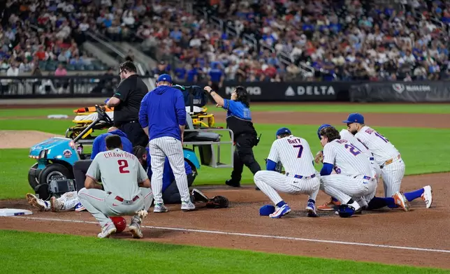 Players looks on as New York Mets first baseman Jared Young is helped bye medical personnel after colliding with pitcher Nolan McLean during the sixth inning of a baseball game against the Philadelphia Phillies, Thursday, Sept. 17, 2026, in New York. (AP Photo/Seth Wenig)