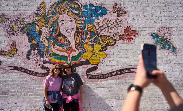 Christy Oakes, left, and Beth Sloan, right, of Kentucky pose with a mural of Dolly Parton Friday, Sept. 25, 2026, in Nashville, Tenn. during Dolly Parton Day honoring the late country music artist. (AP Photo/George Walker IV)