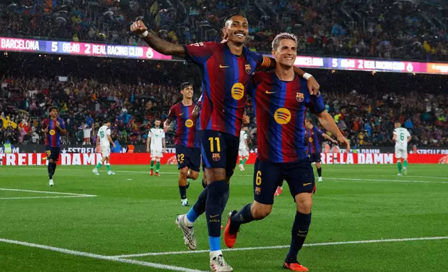 Barcelona's Raphinha celebrates with Gavi, right, after scoring his side's fifth goal from the penalty spot during a Spanish La Liga soccer match between Barcelona and Racing de Santander in Barcelona, Spain, Wednesday, Sept. 16, 2026. (AP Photo/Joan Monfort)