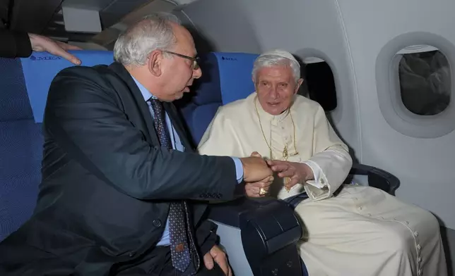 FILE - Rome Bureau Chief Victor Simpson, left, shakes hands with Pope Benedict XVI during the flight from Beirut to Rome, Sept. 16, 2012. (AP Photo/L'Osservatore Romano, File)