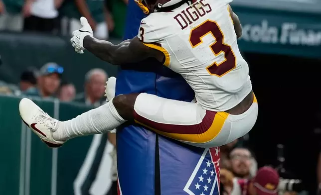 Washington Commanders wide receiver Stefon Diggs (3) jumps on the goal post as he celebrates his touchdown against the Philadelphia Eagles during the second half of an NFL football game, Sunday, Sept. 13, 2026, in Philadelphia. (AP Photo/Matt Slocum)