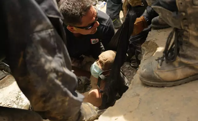 FILE - U.S. firefighters from Fairfax County pull a survivor from the rubble of a building that collapsed in twin earthquakes in La Guaira, Venezuela, June 28, 2026. (AP Photo/Matias Delacroix, File)
