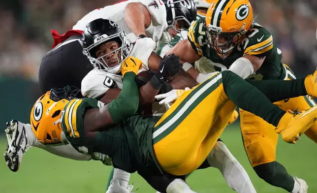 Green Bay Packers' Edgerrin Cooper, left, and Evan Williams , right, stop Atlanta Falcons' Bijan Robinson, center, during the second half of an NFL football game in Green Bay, Wis., Thursday, Sept. 24, 2026. (AP Photo/Abbie Parr)