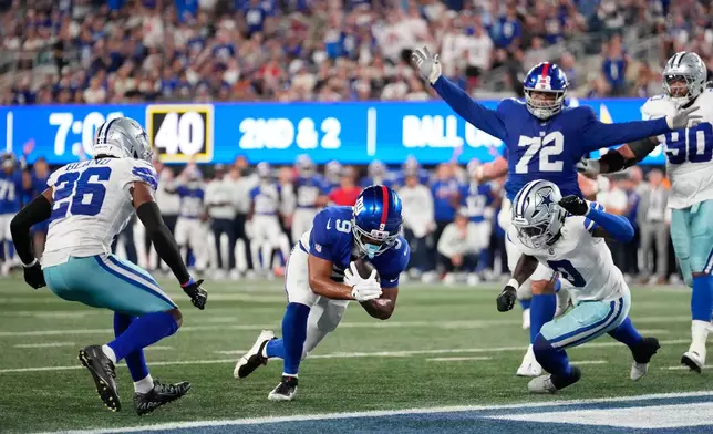 New York Giants tight end Isaiah Likely (9), with teammate guard Jermaine Eluemunor (72) reacting, scores a touchdown run between Dallas Cowboys cornerback Daron Bland (26) and linebacker DeMarvion Overshown (0 ) during the second half of an NFL football game Sunday, Sept. 13, 2026, in East Rutherford, N.J. (AP Photo/Yuki Iwamura)