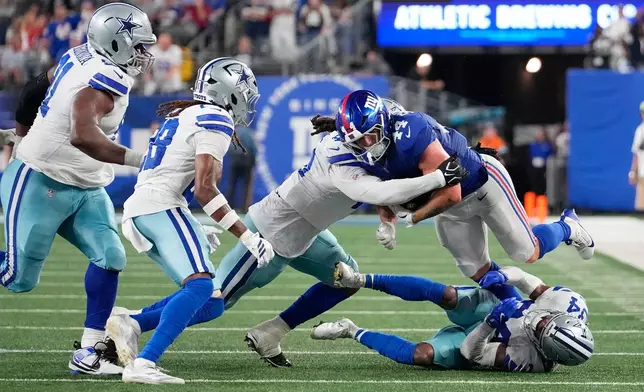 New York Giants running back Cam Skattebo (44) is brought down by a host of Dallas Cowboys defenders during the second half of an NFL football game Sunday, Sept. 13, 2026, in East Rutherford, N.J. (AP Photo/Yuki Iwamura)