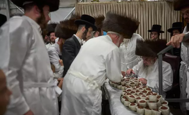 Ultra-Orthodox Jewish men receive cakes from their Rebbe ahead of Yom Kippur, which begins at sunset, in Beit Shemesh, Israel, Sunday, Sept. 20, 2026. (AP Photo/Ohad Zwigenberg)