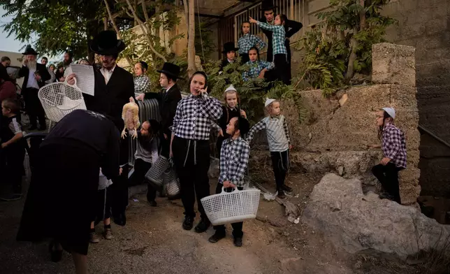 An ultra-Orthodox Jewish man swings a chicken over a woman's head as part of the Kaparot ritual ahead of the Jewish holiday of Yom Kippur in Jerusalem, Thursday, Sept. 17, 2026. (AP Photo/Ohad Zwigenberg)