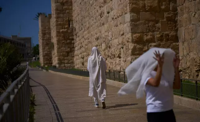 A Jewish man, wrapped in a prayer shawl, walks beside the Old City walls in Jerusalem during the Jewish holiday of Yom Kippur, Monday, Sept. 21, 2026. (AP Photo/Ohad Zwigenberg)