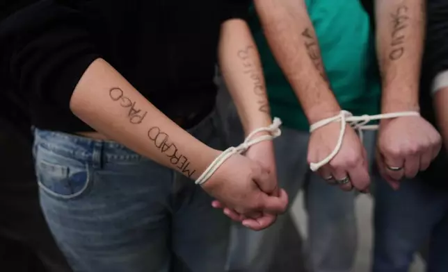 Demonstrators protest with their hands tied outside the Economy Ministry, demanding government action over a household debt crisis, in Buenos Aires, Argentina, Thursday, Aug. 20, 2026. (AP Photo/Victor R. Caivano, File)