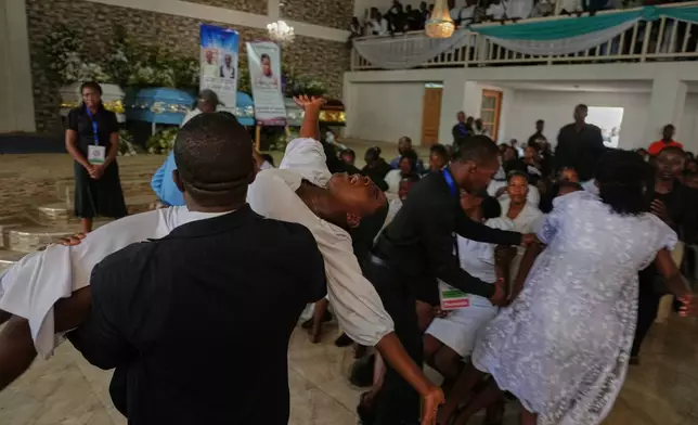 A relative is held as she wails during the funeral service for victims of a gang attack in the Kenscoff neighborhood of Port-au-Prince, Haiti, Wednesday, Sept. 2, 2026. (AP Photo/Odelyn Joseph)