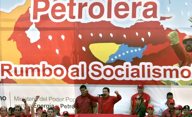 FILE - Venezuela's President Hugo Chavez, center, delivers a speech in front of a banner that reads in Spanish "Oil Company on its way to socialism", to oil workers in Barcelona, Venezuela, Tuesday, May 1, 2007. (AP Photo/Fernando Llano, File)