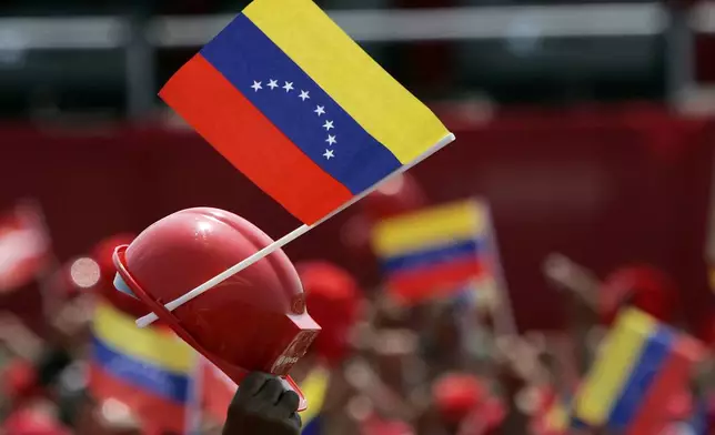 FILE - Venezuelan oil workers wave their helmets and national flags as President Hugo Chavez, unseen, delivers a speech at Jose Antonio Anzoategui oil complex in Barcelona, Venezuela, Tuesday, May 1, 2007. (AP Photo/Fernando Llano, File)
