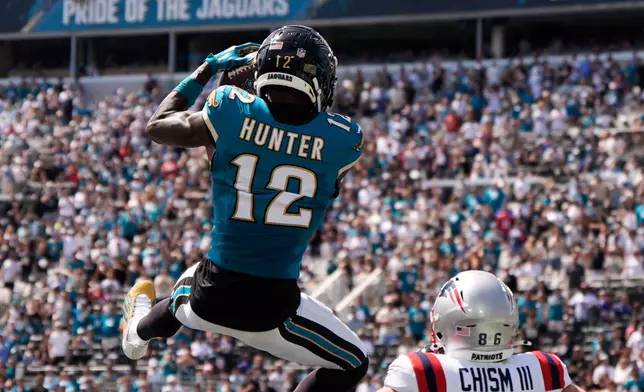 Jacksonville Jaguars wide receiver Travis Hunter (12) intercepts a pass against New England Patriots wide receiver Efton Chism III (86) in the first half during an NFL football game in Jacksonville, Fla., Sunday, Sept. 27, 2026. (AP Photo/Mike Stewart)