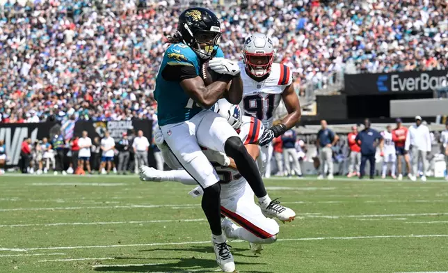 Jacksonville Jaguars wide receiver Josh Cameron (19) makes a catch for a touchdown against New England Patriots linebacker Elijah Ponder (91) and linebacker Christian Elliss (53) in the first half during an NFL football game in Jacksonville, Fla., Sunday, Sept. 27, 2026. (AP Photo/Phelan M. Ebenhack)