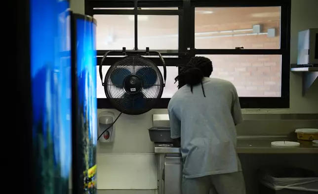 A fan blows air inside while a person who is incarcerated washes dishes in a housing unit at the Minnesota Correctional Facility in Lino Lakes, Minn., Tuesday, Sept. 15, 2026. (AP Photo/Ellen Schmidt)