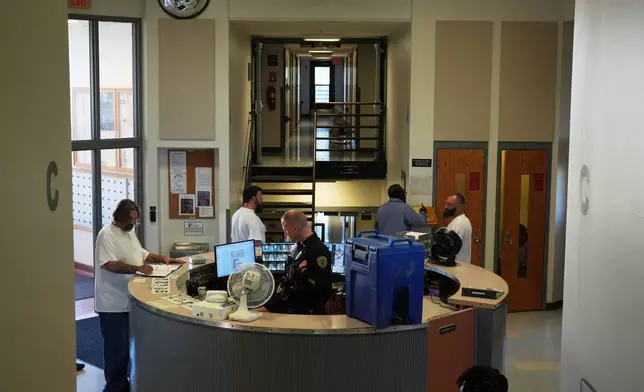 People who are incarcerated roam near the security desk, which is equipped with a fan and water cooler, at a Minnesota Correctional Facility in Lino Lakes, Minn., Tuesday, Sept. 15, 2026. (AP Photo/Ellen Schmidt)