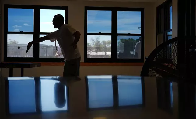 A person who is incarcerated plays ping pong while some windows block light with a reflective coating, meant to lower indoor temperatures, at a Minnesota Correctional Facility in Lino Lakes, Minn., Tuesday, Sept. 15, 2026. (AP Photo/Ellen Schmidt)