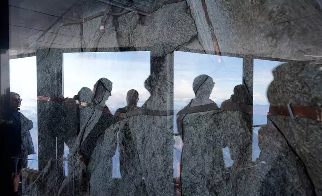Tourists reflected in glass view the Mont-Blanc massif mountains from the Aiguille du Midi, in Chamonix, France, Saturday, Sept. 5, 2026. (AP Photo/Laurent Cipriani)