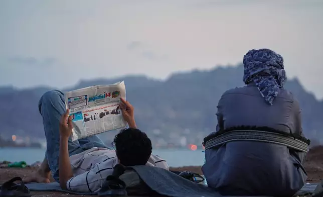 A man reads a newspaper by the sea in government-controlled Aden, Yemen, Friday, Sept. 11, 2026. (AP Photo/Abdulnasser Alseddik)