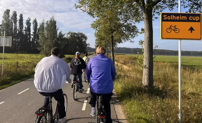In this photo taken with a smartphone, people cycle along the route signposted toward the Solheim Cup venue, Bernardus Golf in Den Bosch, Netherlands, Saturday Sept. 12, 2026. (AP Photos/Mike Corder)