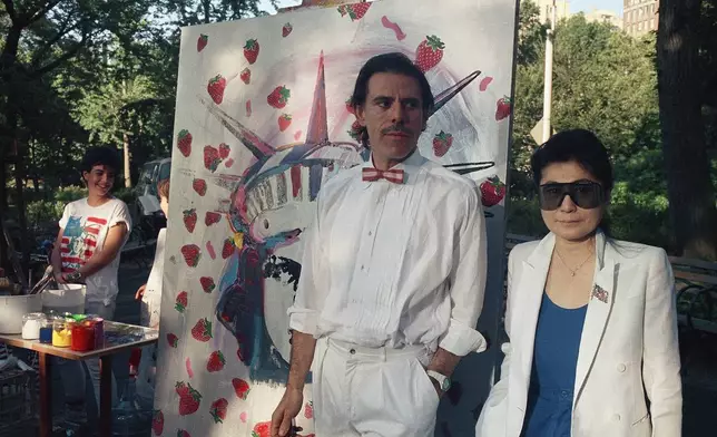 FILE - Artist Peter Max, left, and Yoko Ono pose together at Central Park with a Statue of Liberty-Strawberry Fields mural on July 4, 1986, in New York. (AP Photo/David Bookstaver, File)
