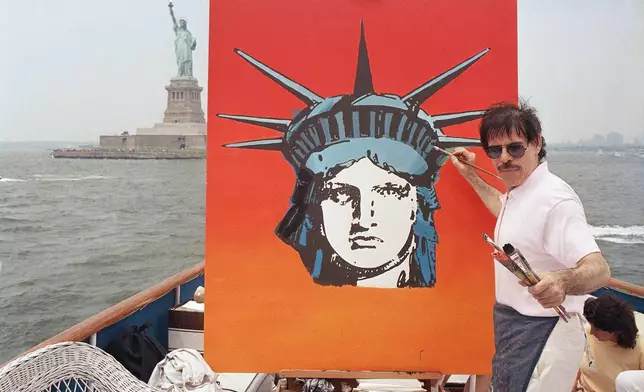 FILE - Artist Peter Max works on a painting of the Statue of Liberty aboard a boat in New York Harbor, July 4, 1987, in New York. (AP Photo/David Bookstaver, File)