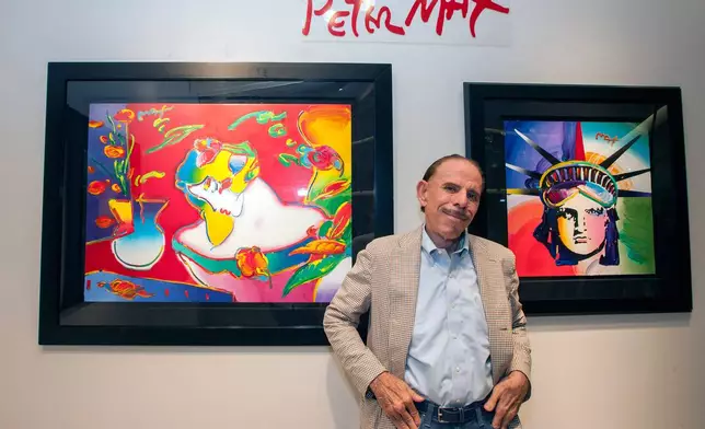 FILE - Artist Peter Max poses for a photo during his retrospective with the Road Show Company exhibit, Sept. 6, 2014, in Northbrook Court mall in Northbrook, Ill. (Photo by Barry Brecheisen/Invision/AP, File)