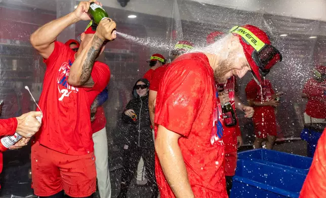 Philadelphia Phillies celebrate in the clubhouse during a celebration after the team clinched a Wild Card slot in the postseason by defeating the Tampa Bay Rays in a baseball game Sunday, Sept. 27, 2026, in Philadelphia. (AP Photo/Laurence Kesterson)