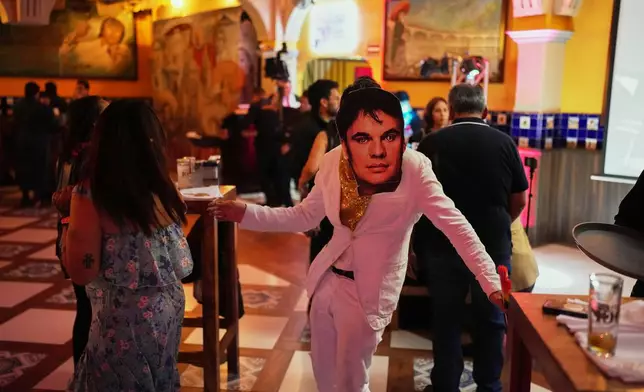 A music fan wearing a mask of Mexican singer-songwriter Juan Gabriel dances during a tribute ahead of the 10th anniversary of his death at Tenampa bar in Mexico City, Thursday, Aug. 27, 2026. (AP Photo/Eduardo Verdugo)