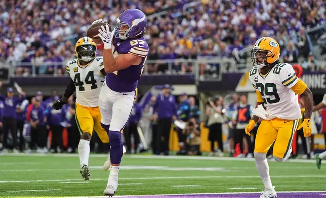 Minnesota Vikings tight end T.J. Hockenson (87) catches a touchdown pass as Green Bay Packers' Zaire Franklin (44) and Xavier McKinney (29) look on during the second half of an NFL football game, Sunday, Sept. 13, 2026, in Minneapolis, Minn. (AP Photo/Abbie Parr)