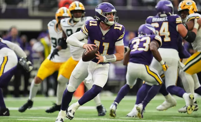 Minnesota Vikings quarterback Carson Wentz (11) rolls out of the pocket before throwing a pass during the second half of an NFL football game against the Green Bay Packers, Sunday, Sept. 13, 2026, in Minneapolis, Minn. (AP Photo/Abbie Parr)