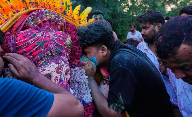 Devotees whisper their wishes in the ears of an idol of the elephant-headed Hindu god Ganesha before immersion in a makeshift pond during Ganesh Visarjan in New Delhi, India, Friday, Sept. 25, 2026. (AP Photo/Manish Swarup)